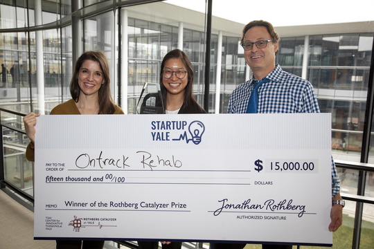 Student holds giant check with prize leaders